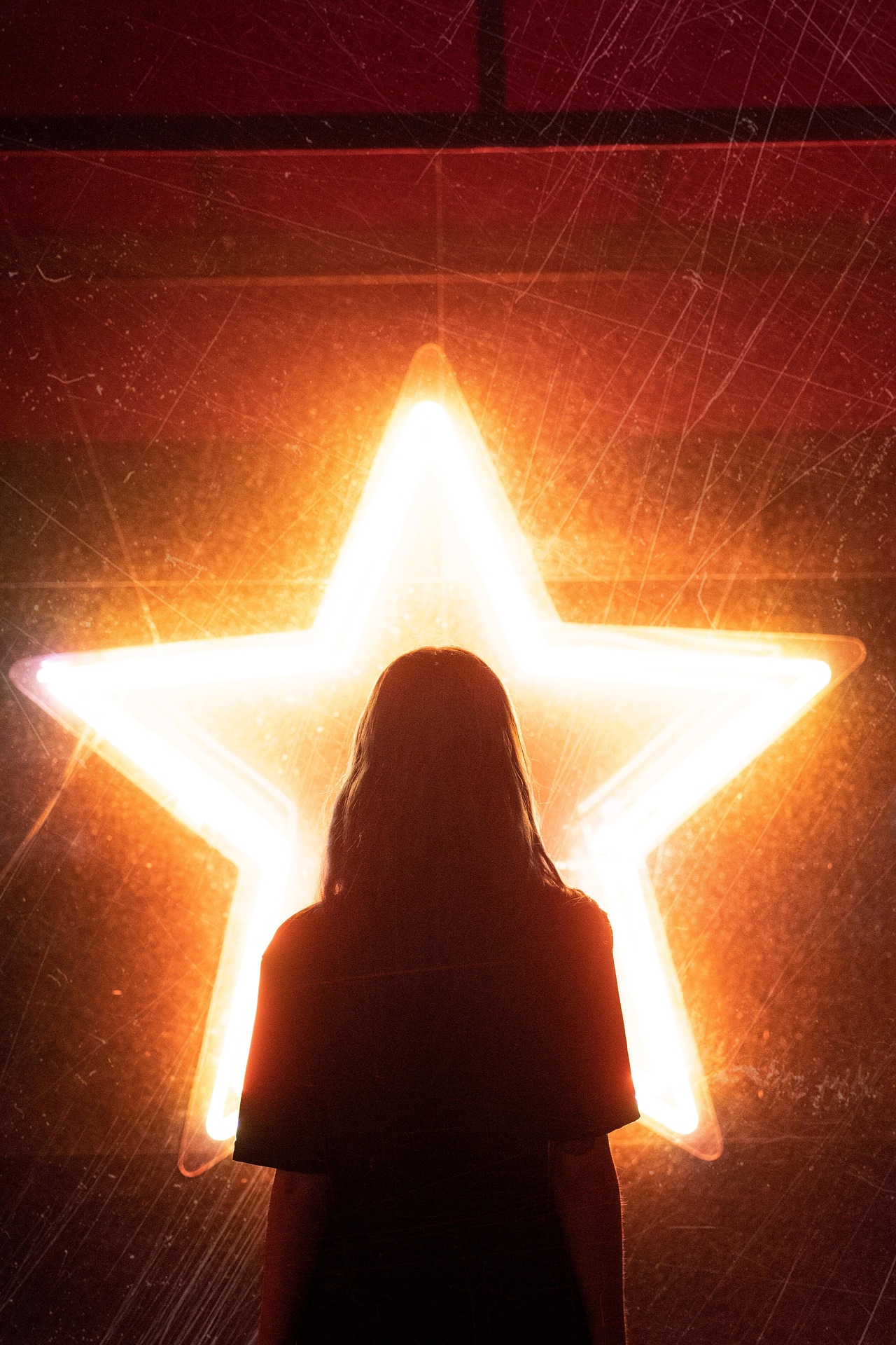 A silhouetted woman faces a large pentagram of light