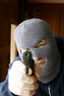 A masked man points a gun directly at us