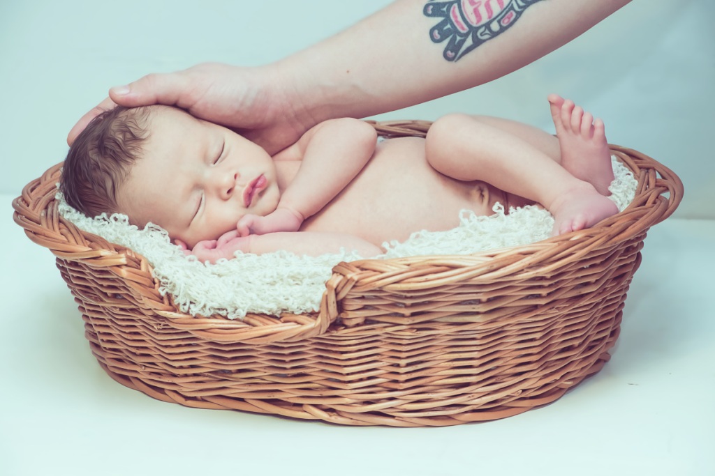 Baby asleep in comfy basket being caressed