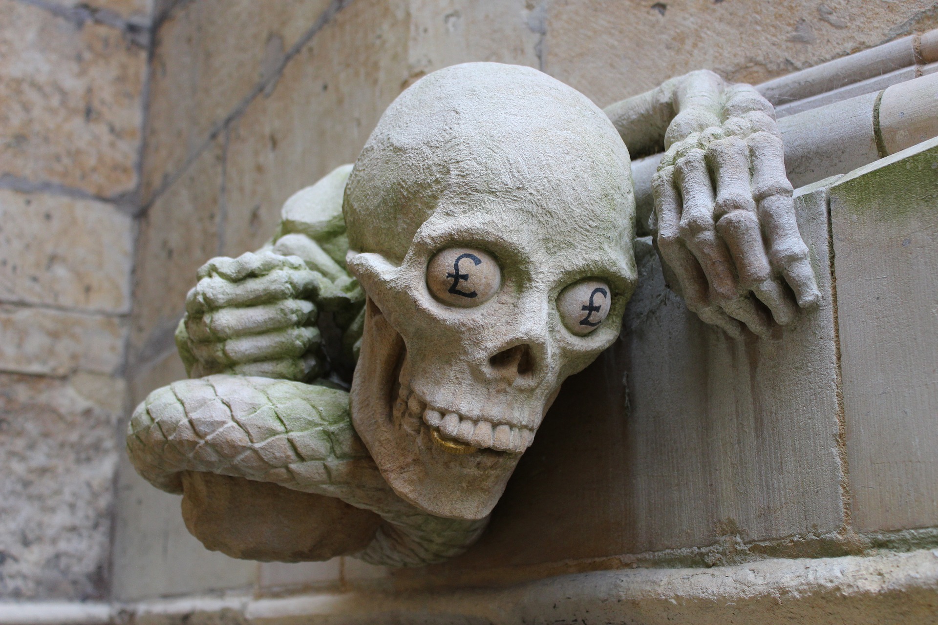 A stone sculpture on a church of a skull with bulging £ eyeballs and bony hands and serpent tail