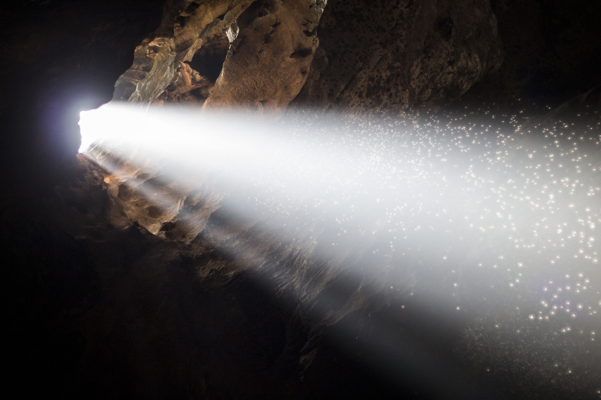 Through a hole in a cave's wall, a large shaft of bright morning light has arrived