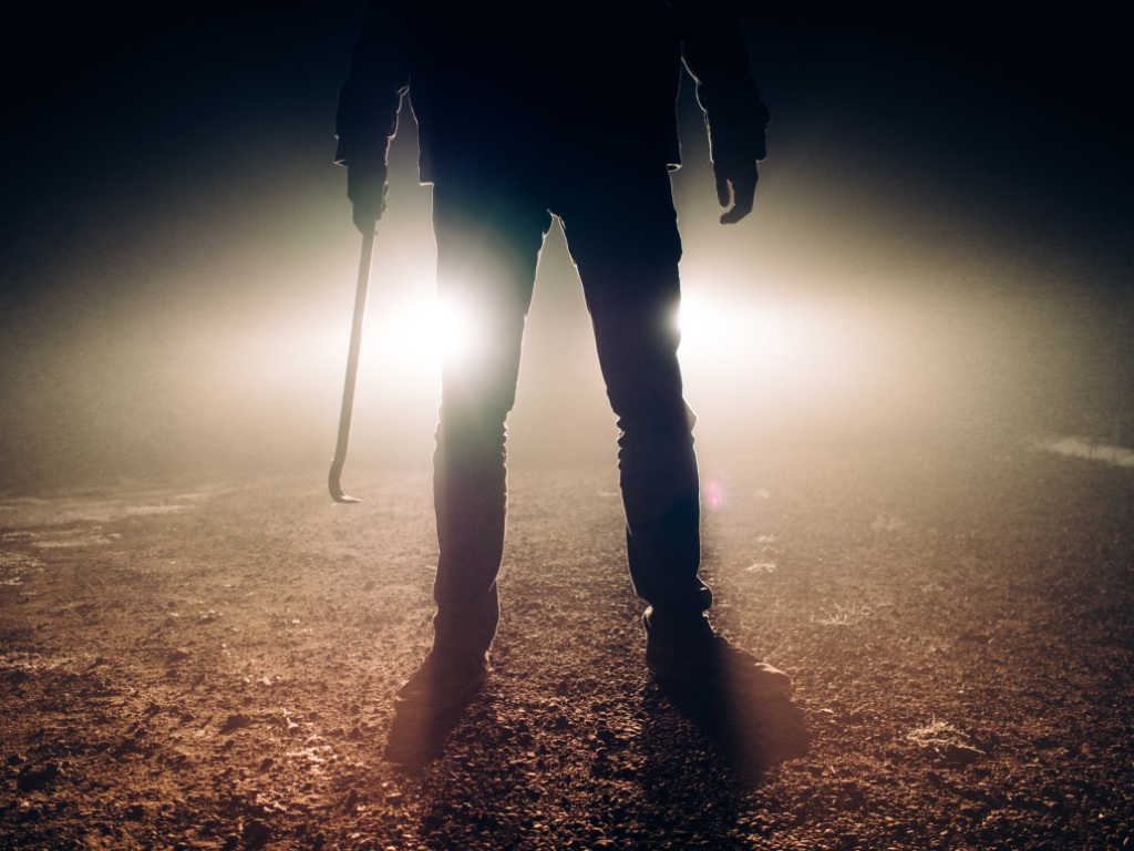 Man with crowbar in headlights