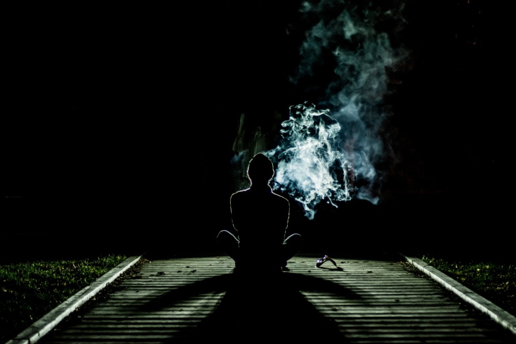 Seated person on rail tracks using drugs at night