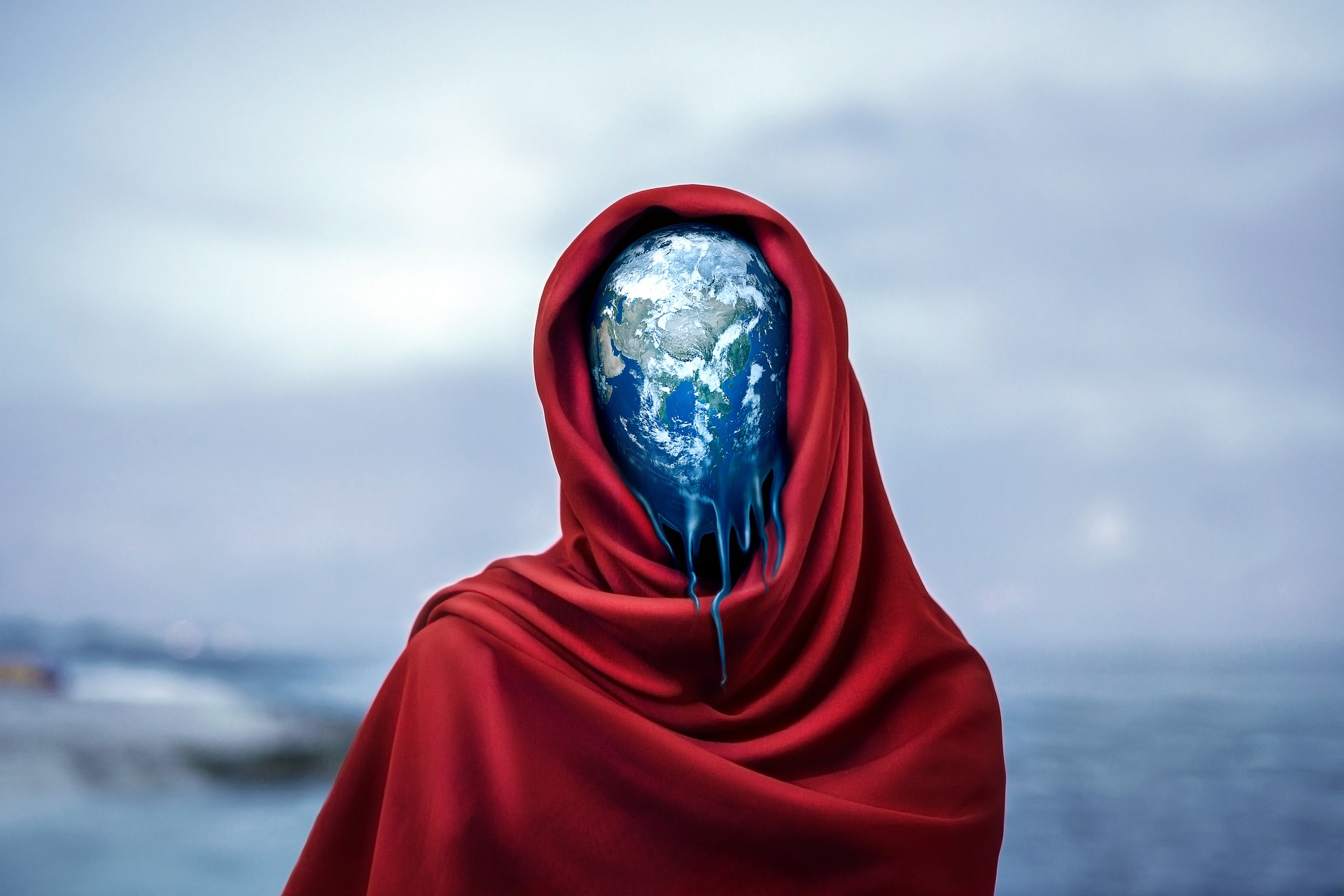 The planet Earth appears as a head within a blood-red head-shawl. The Earth appears to be melting from its base, like candle-wax melt.
