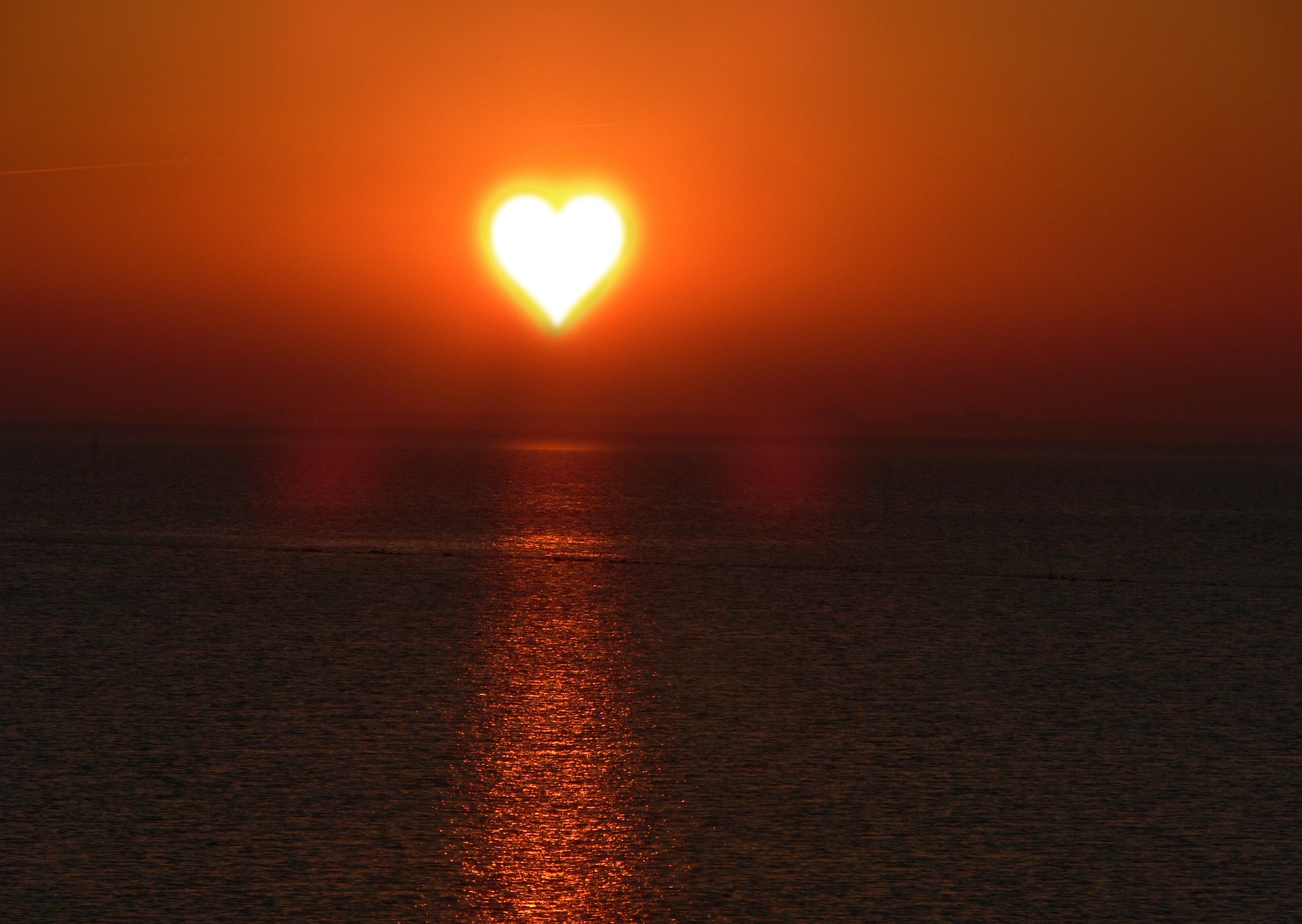 A sun in the shape of a heart is on the horizon. It illuminates all.
