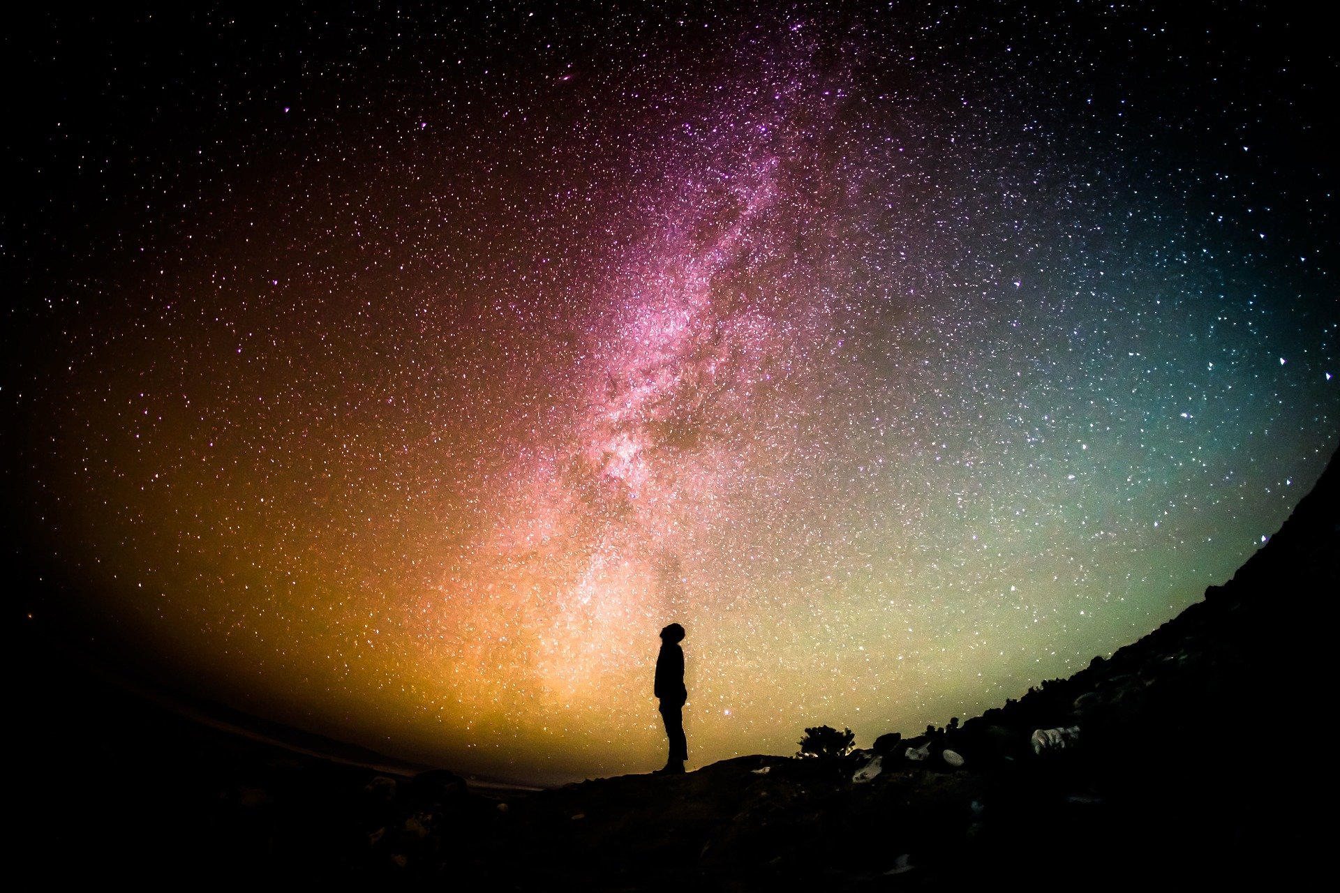 Silhouetted person under spectacular starry sky, gazing up