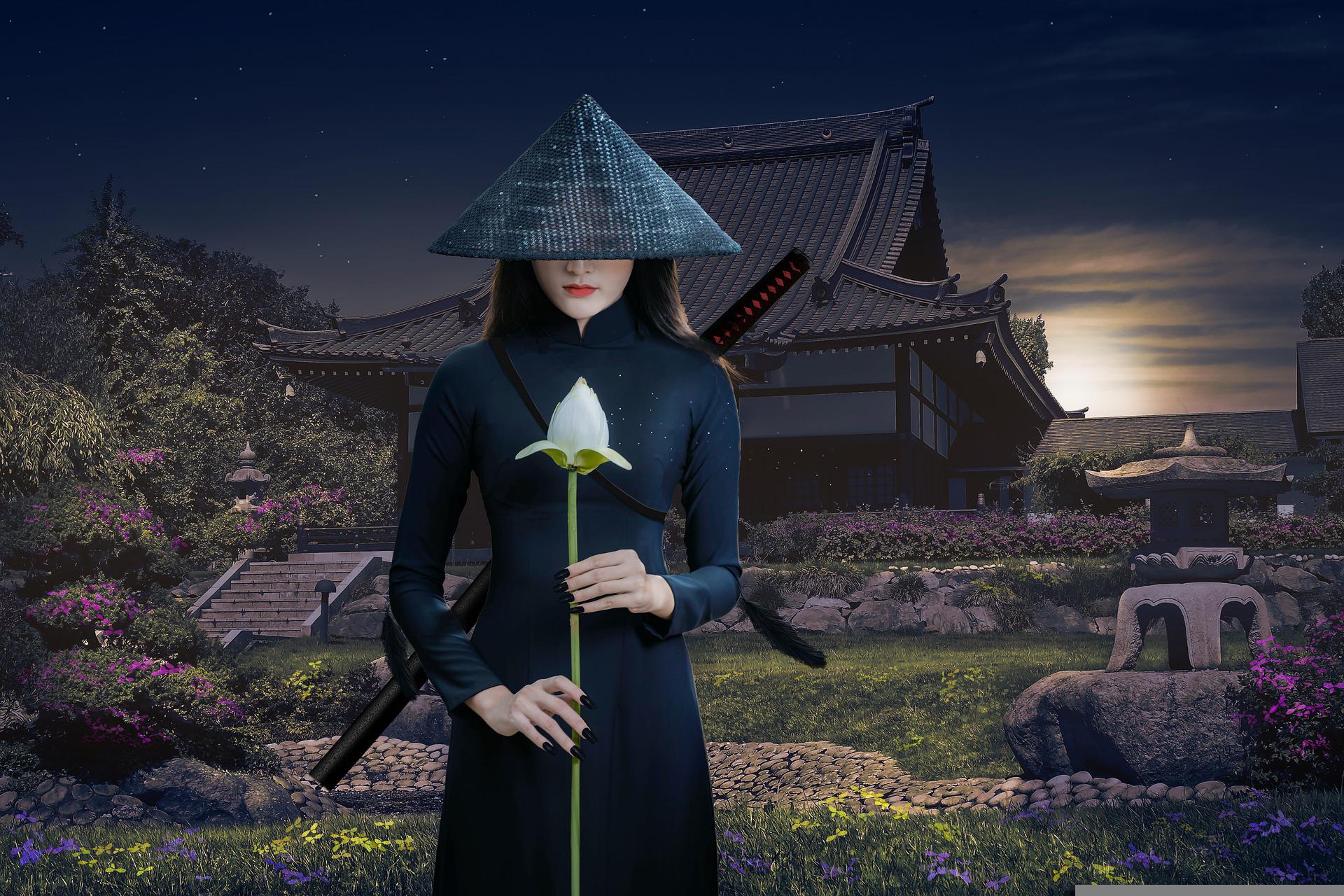 A slim woman in a black kimono and conical hat stands holding the stalk of a beautiful white flower. On her back is a sheathed katana. Around her is a magical garden with many beautiful flowers. A Shinto temple is in the background, with the sun peaking from behind it. A starry sky is still visible too.