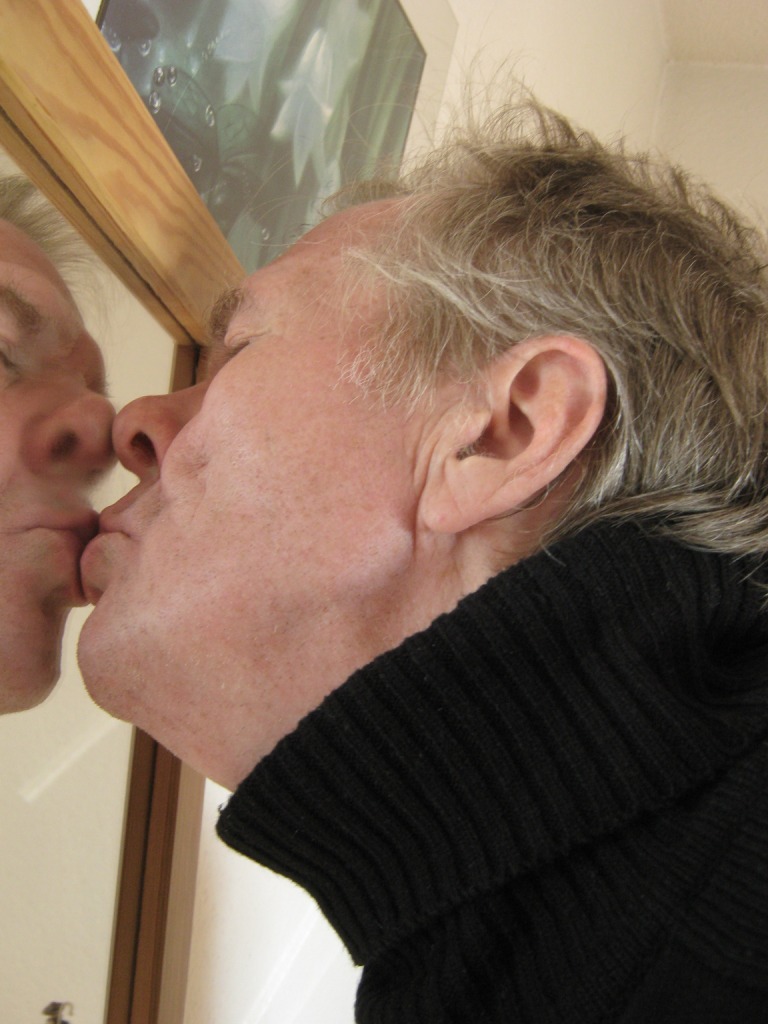 Mature man kisses himself in a mirror