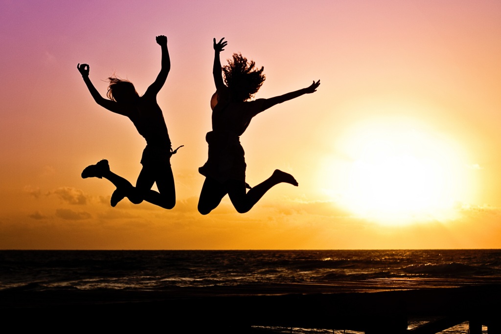 Sun Freedom (two youths jump at sunrise beach)