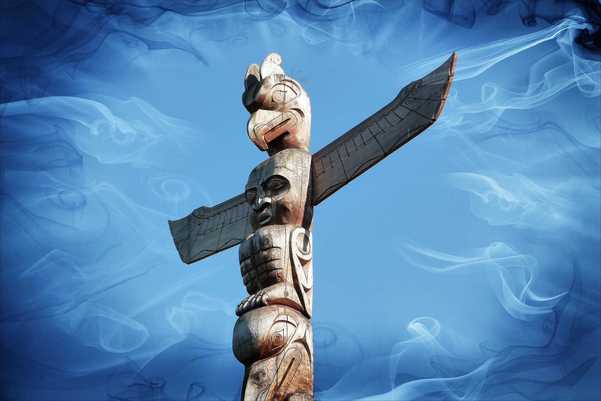 The top of a North American Indian totem pole. Around the carved creatures is a shimmering blue light.