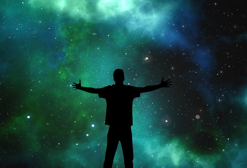 Silhouette of a man, arms outstretched, embraces the Universe