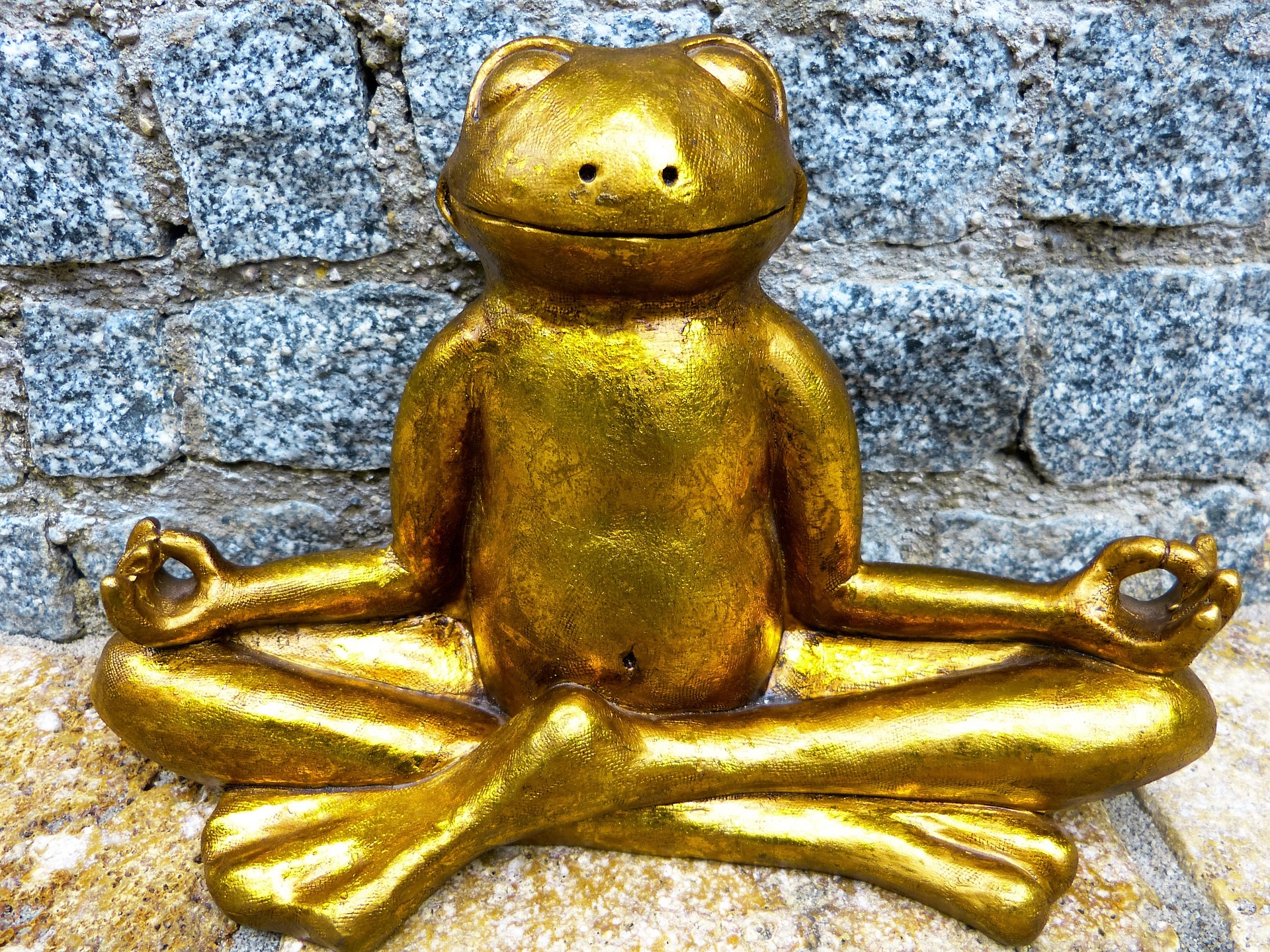 A statue of a golden frog in a cross-legged meditation pose