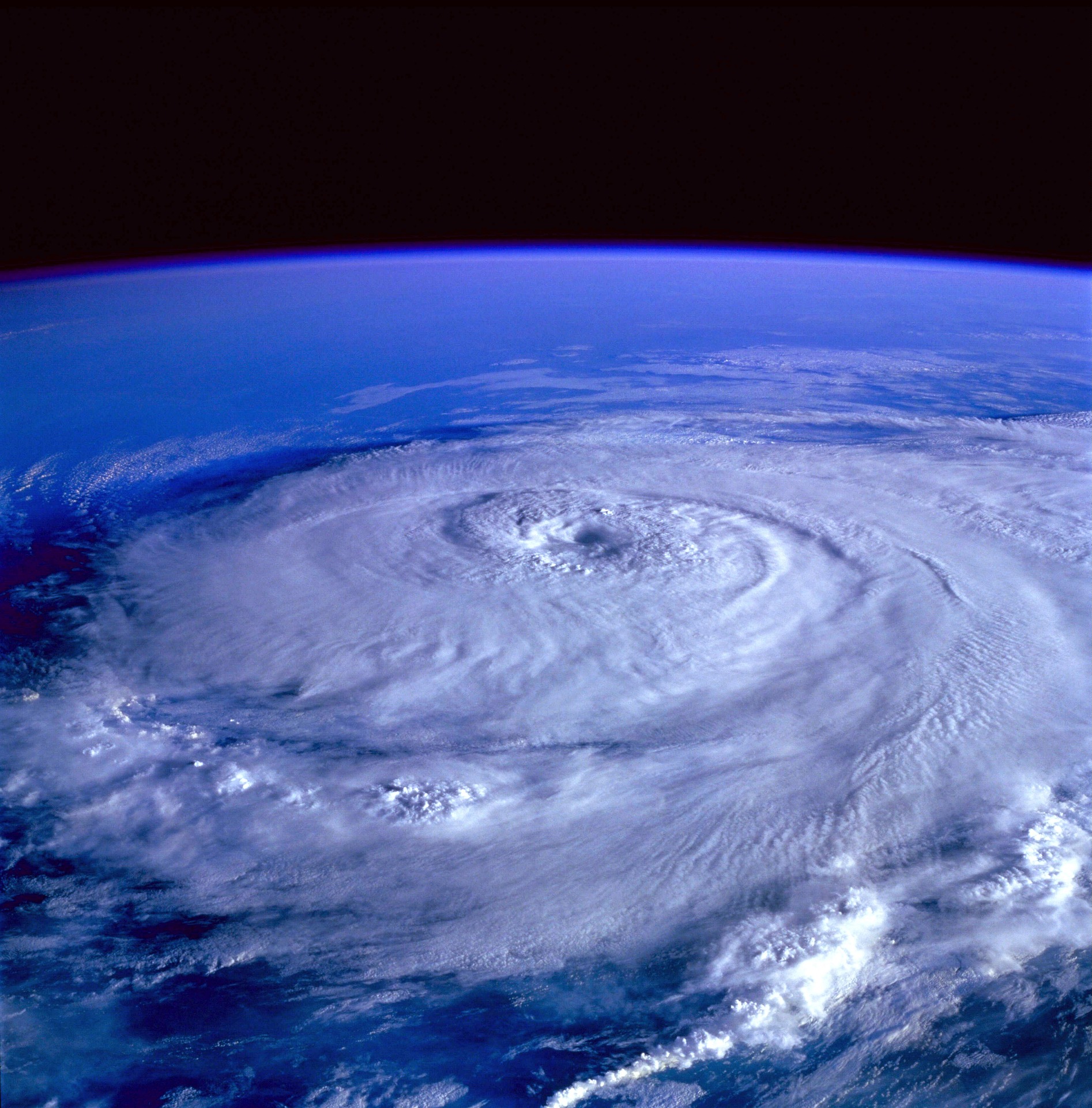 The top of a hurricane seen from outer space. The background has a deep blue hue.