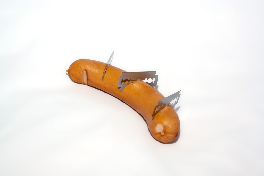 Sausage with three razors cutting into it